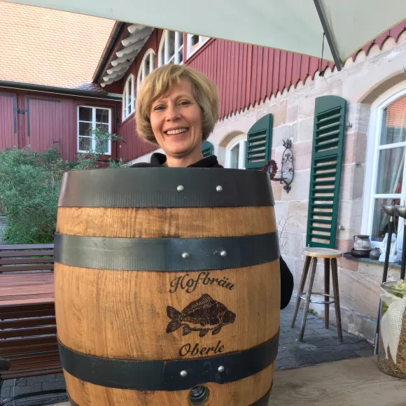 Seniorchefin der Fischerei Oberle vor einem Bierfass der Hofbräu Oberle