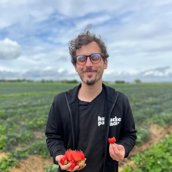 Person steht mit Erdbeeren auf einem Feld