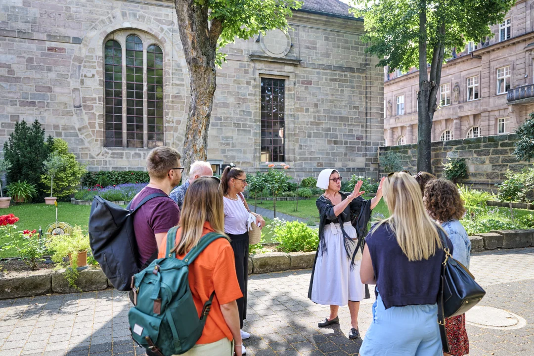 Eine Stadtführung im Innenhof der Hugenottenkirche mit der kostümierten Hugenottin